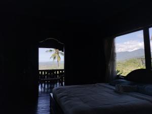 a bedroom with a bed and a window with a view at D'kailash Retreat in Singaraja