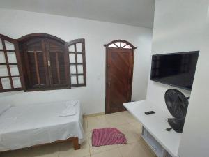 uma sala de estar com televisão e uma sala em Confortáveis e práticas Kitnets em Belo Horizonte em Venda Nova