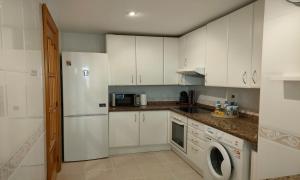 a kitchen with white cabinets and a washer and dryer at Apartamento en Marbella junto a campos de golf in Marbella