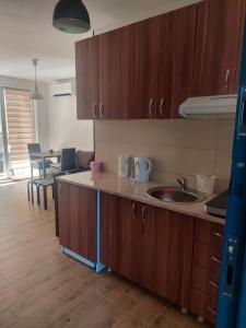 a kitchen with wooden cabinets and a living room at Apartman Todor in Veliko Gradište
