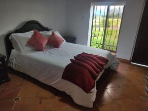 Una cama con sábanas blancas y almohadas rojas. en Cabañas & Glamping ILLARI Boutique, en Paipa