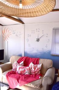 a clock on a wall above a couch with pillows at Pips Chalet rest and relax in the Isle of Sheppey in Sheerness