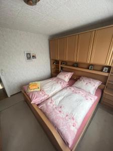 een bed met roze lakens en een boek erop bij Puppenhaus 