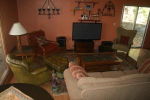 sala de estar con muebles y TV de pantalla plana. en Sunny Pines Cottage en Mariposa