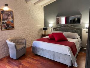 una camera con letto, cuscino rosso e sedia di Vi Ja Villa Janas Cagliari Resort a Cagliari