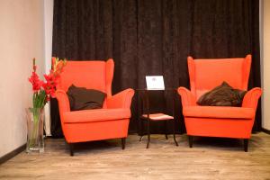 モスクワにあるKvart-Hotel Love Moscowのオレンジの椅子2脚、花瓶付きテーブル