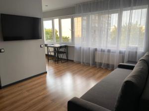 uma sala de estar com um sofá e uma televisão de ecrã plano em Akropole Apartment em Riga