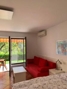 ein Wohnzimmer mit einem roten Sofa und einem Bett in der Unterkunft Apartments Krkoč in Izola