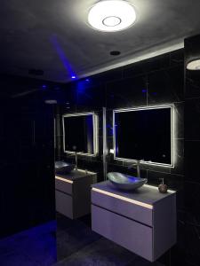 een badkamer met twee wastafels en twee monitors aan de muur bij Chambre romantique avec Spa B in Gruny