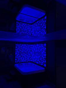 een donkere kamer met blauwe verlichting en een spiegel bij Chambre romantique avec Spa B in Gruny