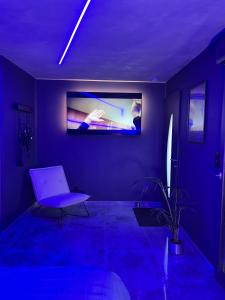 een blauwe kamer met een stoel en een foto aan de muur bij Chambre romantique avec Spa B in Gruny
