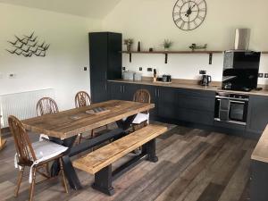 a kitchen with a wooden table and chairs and a counter at River Cottage in Portglenone