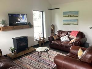 a living room with a leather couch and a fireplace at River Cottage in Portglenone