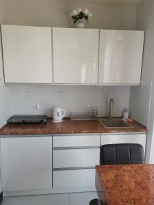 a kitchen with white cabinets and a sink and a table at Apartament prywatny z aneksem kuchennym w hotelu Royal Tulip Sand in Kołobrzeg