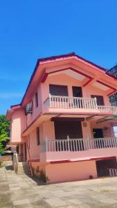 une maison rose avec un balcon latéral dans l'établissement The Sea Breeze, à Nuvem