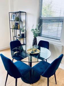 a dining room with a glass table and blue chairs at Luxury Double Bedroom, near Heathrow Airport in Hillingdon