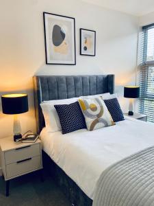 a bedroom with a bed with pillows and two lamps at Luxury Double Bedroom, near Heathrow Airport in Hillingdon