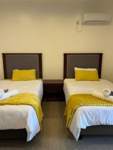 Duas camas com almofadas amarelas num quarto em Njikale Serviced Apartments - 6 em Lusaka