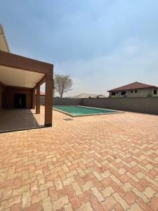 um pátio de tijolos com um campo de golfe ao fundo em Njikale Serviced Apartments - 6 em Lusaka