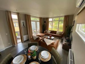 a living room with a table and a couch at Kindvriendelijk luxe chalet in de bossen met privé sauna in Harderwijk