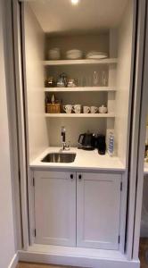 a kitchen with a sink and shelves with dishes at The Annex is in the beautiful Ashdown Forest in Crowborough