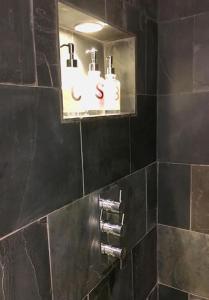 a black tiled bathroom with a soap dispenser on a wall at The Annex is in the beautiful Ashdown Forest in Crowborough