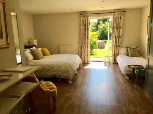 a bedroom with two beds and a sliding glass door at The Annex is in the beautiful Ashdown Forest in Crowborough