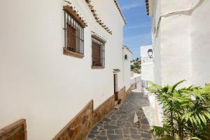 a narrow alleyway between two white buildings with windows at Casa Canillas - for solo travelers or small groups of 4 to 6 people in Canillas de Aceituno