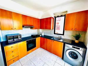 a kitchen with wooden cabinets and a washing machine at Mackenzie apartment 301 in Larnaca