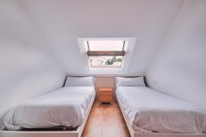 two beds in a small room with a window at Palmeira Vistamar by Serendipia Turismo in San Pedro