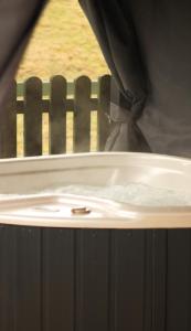 a person standing in a bath tub with a window at Blodyn Cottage - Cosy, Self-Catering with Private Hot Tub in Bodfari