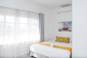 a white bedroom with a bed and a window at 57 on Lorne Guesthouse in Estcourt
