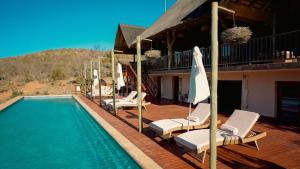 a deck with chairs and a swimming pool at Shibula Solar Safari Big 5 Lodge in Welgevonden Game Reserve