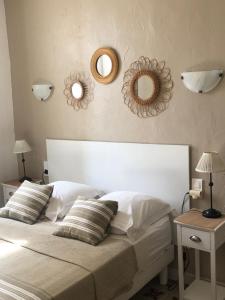 um quarto com uma cama branca e dois espelhos na parede em Maison au bord de mer em Saintes-Maries-de-la-Mer