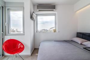 a bedroom with a red chair and two windows at Kolonaki Square Parthenon Τerrace in Athens