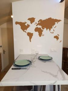 a white table with two plates and a world map on the wall at Le studio de Diane - Terrasse et Parking - in Montboucher-sur-Jabron