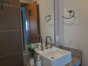 Un baño con un lavabo blanco y un espejo. en Apartamento uma quadra do mar, melhor localização, en Capão da Canoa 25 fotos más