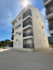 a white apartment building with a car parked in front at Apartment Stex 2 in Podgorica