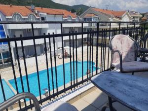 a balcony with a table and chairs and a swimming pool at Nearby PORTONOVI-Norwegian-village DUPLEX in Đenovići