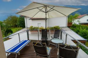 balcón con mesa, sillas y sombrilla en Ferienhaus Tolazzi, en Arnoldstein