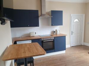 uma cozinha com armários azuis e uma mesa de madeira em Town View em Stourport