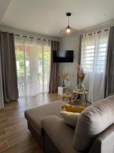 ein Wohnzimmer mit einem Sofa und einem Tisch in der Unterkunft Résidence Terre et Passion in Ducos