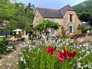 una casa con un jardín con flores delante en Esparoutis en Saint-Cybranet