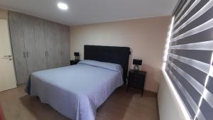 um quarto com uma cama branca e uma cabeceira preta em Departamento Centro Lynch II em Temuco
