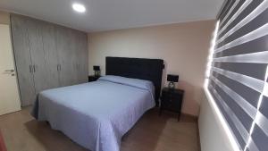 Un dormitorio con una cama blanca y un cabecero negro. en Departamento Centro Lynch II, en Temuco
