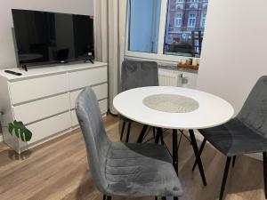 シュフィドニツァにあるLa Mia Casa Apartament Świdnicaのテーブル、椅子、テレビが備わる客室です。