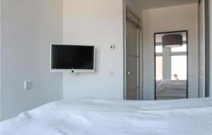 een witte slaapkamer met een bed en een tv aan de muur bij Duinzicht 2 in Bergen aan Zee