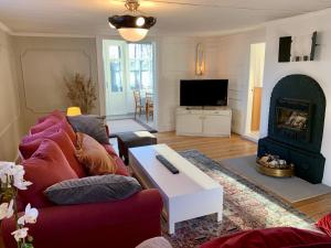 uma sala de estar com um sofá vermelho e uma lareira em Flemma Gård Wing residence with lake view em Vreta Kloster