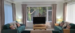 een woonkamer met 2 banken en een flatscreen-tv bij Annie's House with Thermal Health Spa in Moville