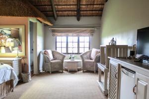 a bedroom with two chairs and a bed and a window at Siesta Guesthouse & Wedding Venue - Frankfort in Frankfort